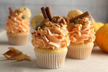 Renkli kremalı, baharatlı, kurabiyeli, fındıklı ve sonbahar desenli kapkekler gri masada, yakın plan.