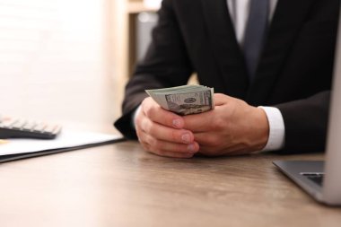 Ahşap masada dolar sayan adam, yakın plan.