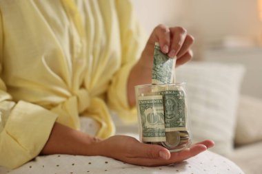 Kadın parayı yatağın içinde kavanoza koyuyor, yakın plan.