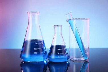 Ayna yüzeyinde mavi sıvı bulunan farklı cam kaplama renk arkaplanına karşı