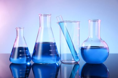 Ayna yüzeyinde mavi sıvı bulunan farklı cam kaplama renk arkaplanına karşı