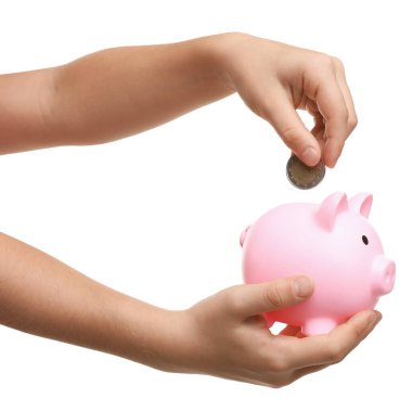 Küçük kız cep harçlığını beyaz arka planda kumbaraya yatırıyor.