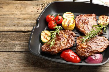 Izgara biftekli tava, biberiye ve sebzeler ahşap masada, yakın plan. Metin için boşluk