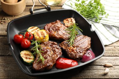 Tavada ızgara biftek, biberiye ve sebzeler ahşap masada, yakın plan.