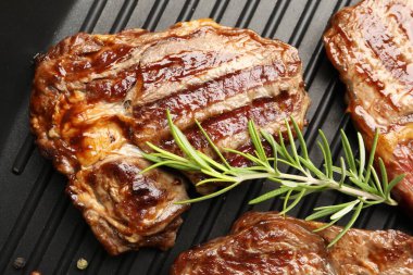 Izgara biftek, biberiye ve siyah tavada biberiye, yakın plan.