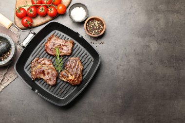 Izgara biftekli tava, biberiye, domates ve baharatlı gri desenli masa, düz yatak. Metin için boşluk