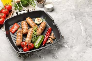 Izgara sosis, sebze, mantar ve baharatlı tava. Gri desenli masa, yakın plan.