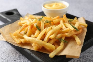 Tasty french fries with sauce on light grey table, closeup