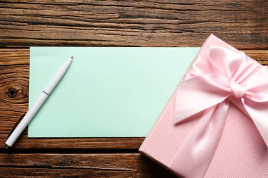 Boş kart, kalem ve hediye kutusu ahşap masada, düz yatıyordu.