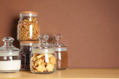 Cam kavanozlar, kahverengi arka plandaki ahşap masada farklı ürünler. Metin için boşluk