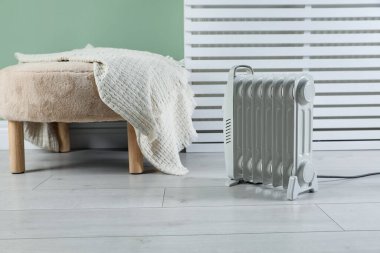 Elektrikli ısıtıcı ve yumuşak ahşap zeminde battaniyeli puf.