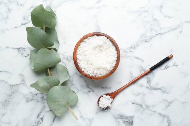 Deniz tuzu kasede, kaşıkta ve okaliptüs dalında beyaz mermer masada, düz yerde.