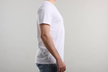 Açık gri arka plan yakınlarında şık beyaz tişörtler giyen genç adam, yakın plan. Tasarım için model