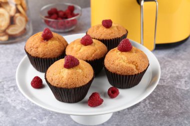 Gri desenli masada ahududu ve hava fritözlü lezzetli kekler, yakın plan.