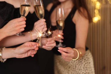 Yeni yılı evde maytap ve şarap kadehleriyle kutlayan kadınlar, yakın plan.