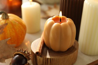 Yanan balkabağı şekilli mum ve beyaz masa üzerinde güzel mumlar, yakın plan. Sonbahar havası