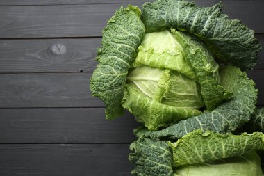 Fresh Savoy cabbages on black wooden table, flat lay. Space for text