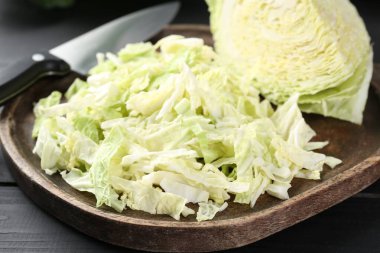 Fresh shredded Savoy cabbage and knife on black wooden table, closeup