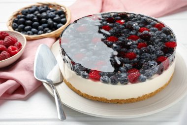 Böğürtlenli lezzetli cheesecake beyaz ahşap masada servis ediliyor, yakın plan.