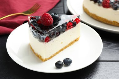 Piece of delicious cheesecake with berries on black wooden table, closeup