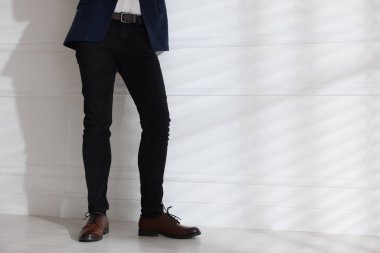 Beyaz duvarın yanında şık kotlu bir adam, yakın plan. Metin için boşluk