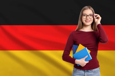 Almanya bayrağına karşı gözlüklü ve defterli öğrenci. Dil okulu