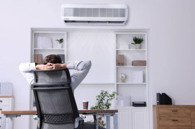 Ofiste klima altında çalışan bir işçi. Sıcaklığı korumak için