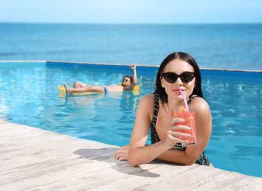 Çift, okyanus manzaralı havuzda dinleniyor.