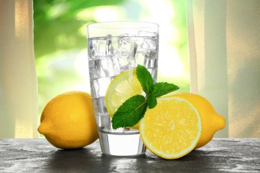 Odanın penceresine karşı limon ve buzla su serinletiyorum.