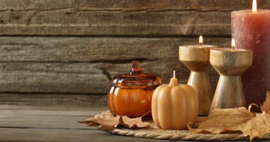 Sonbahar atmosferi. Ahşap masada mum yakan kadın, yakın plan. Metin için boşluk