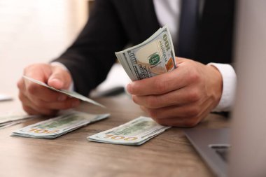 Ahşap masada dolar sayan adam, yakın plan.