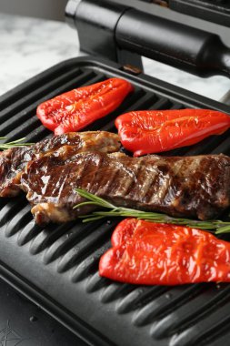 Biftekli ızgara, dolmalık biber ve biberiye beyaz masada, yakın plan.