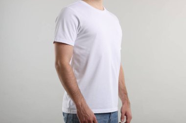 Açık gri arka plan yakınlarında şık beyaz tişörtler giyen genç adam, yakın plan. Tasarım için model