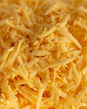 Sliced cheese in a kitchen plate. Cutting on a grater. Natural dairy ingredient for cooking. Delicious, healthy, vegetarian and diet food. Closeup photo