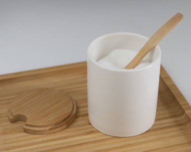 Beyaz şekerli mutfak kavanozu. Tahta kaşık ve ayağa kalk. Tatlı için tatlı malzemesi. Yakın plan fotoğraf.