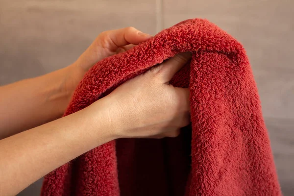 Female hands and red towel. The woman is washing, wiping her hands. Bathroom home. Body care, health and hygiene. Photo closeup