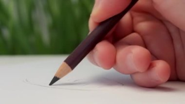 Bir erkek eli bir kağıt parçasına kurşun kalemle çizer. Sanatsal alet. Bir kadın portresi çiziyorum. Fikir, hobi ve yaratıcılık. Video kapanışı