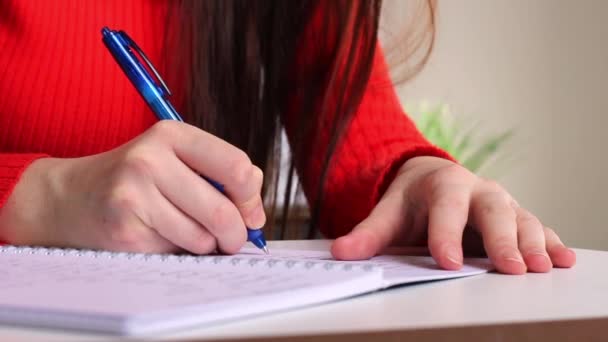 Een Meisje Aan Tafel Schrijft Met Een Pen Een Notitieboekje — Stockvideo