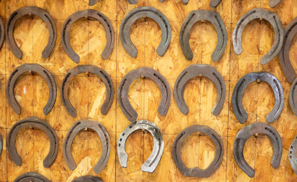 Horseshoes hang on the wall. Farm forge. Forged metal horse hoof guard