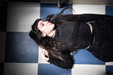 Gotik görünümlü, siyah elbiseli, yerde yatan güzel bir kız. Moda kavramına gözü kapalı çekici bir kadın.