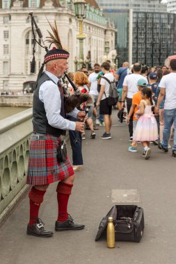 Londra, İngiltere - AUG 03, 2024 - Bir İskoç müzisyen Westminster Köprüsü 'nde gayda çalıyor. Arka planda bir grup turist görülebilir