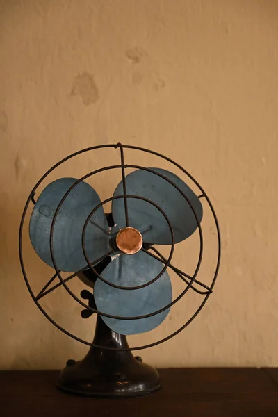 One antique blue fan against brown cement wall