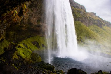 Seljalandsfoss Iceland is a stunning waterfall that allows visitors to walk behind the cascading water.