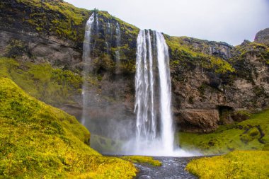 Seljalandsfoss Iceland is a stunning waterfall that allows visitors to walk behind the cascading water.