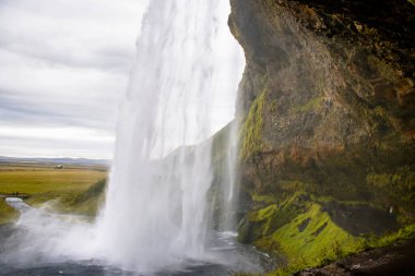 Seljalandsfoss Iceland is a stunning waterfall that allows visitors to walk behind the cascading water.
