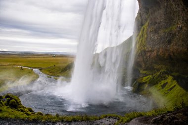 Seljalandsfoss Iceland is a stunning waterfall that allows visitors to walk behind the cascading water.