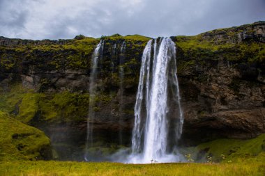 Seljalandsfoss Iceland is a stunning waterfall that allows visitors to walk behind the cascading water.