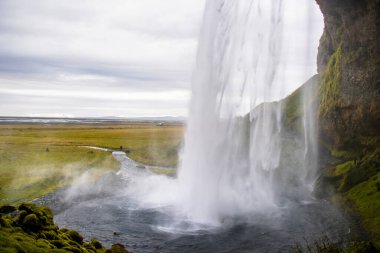 Seljalandsfoss Iceland is a stunning waterfall that allows visitors to walk behind the cascading water.