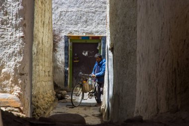 Lo Manthang, Nepal - 23 Temmuz 2023: Nepal 'in Yukarı Mustang' inde Lo Manthang caddelerinde bisikletli bir işçi