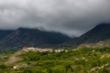 Muktinath, Mustang, Nepal 'deki Sisli Dağlar ve Uzak Evlerle Karanlık Dramatik Çöl Manzarası